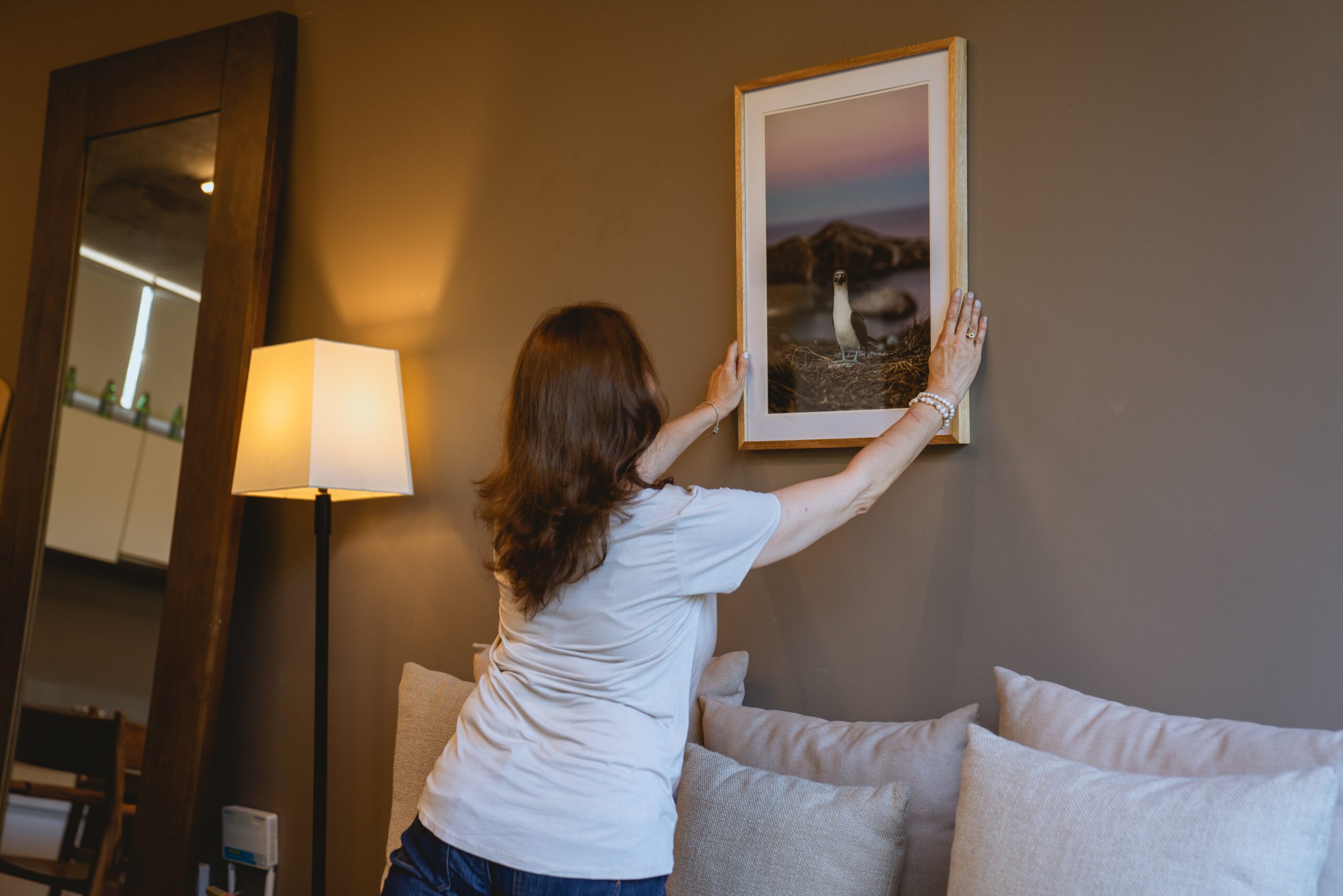 vrouw hangt schilderij aan de muur
